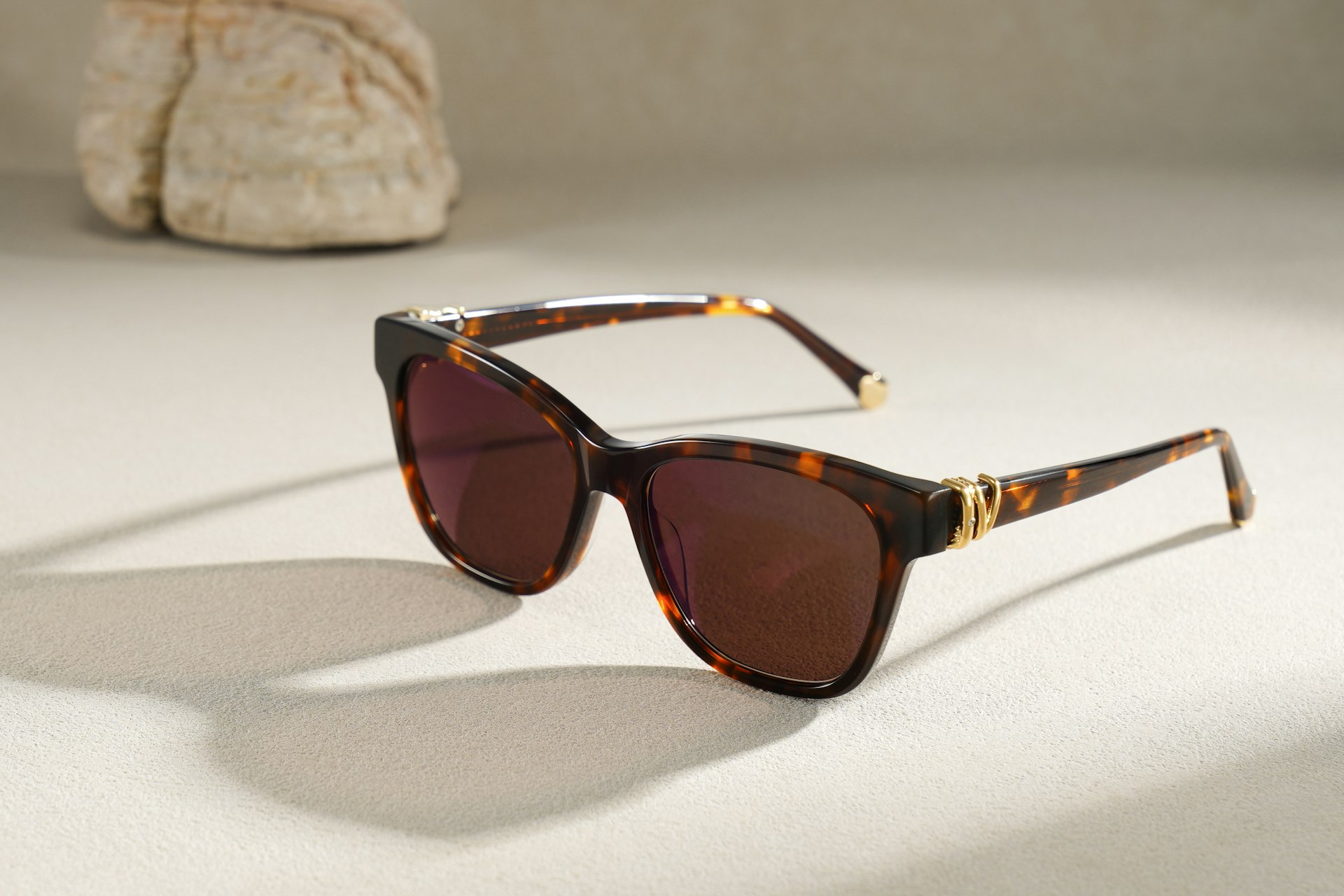 Tortoiseshell sunglasses with gold accents on a light surface.